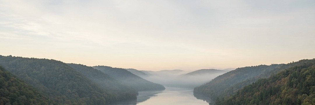 The river valley at dawn, fog holding low between the hills